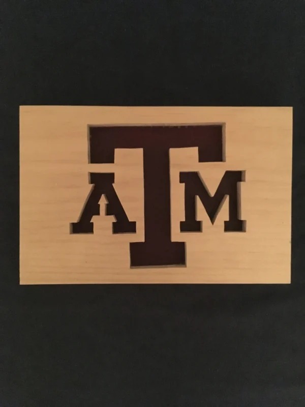 Wooden plaque with the A&M College symbol on it