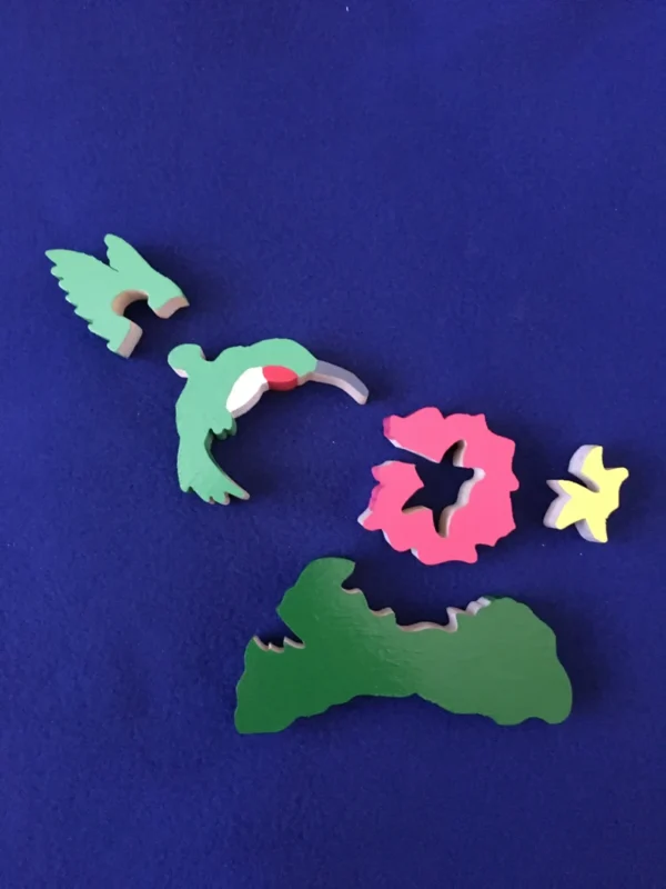 Separated pieces of a wooden painted hummingbird puzzle