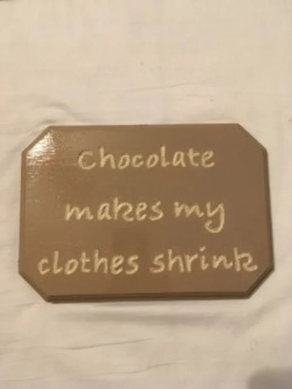 Brown wooden plaque that says "Chocolate makes my clothes shrink"