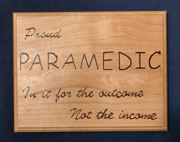 Wooden plaque that says "Proud Paramedic: In it for the outcome, not the income"