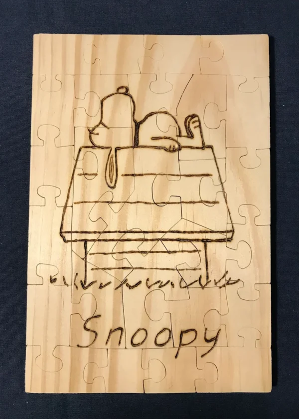 Wooden puzzle of a wood burned Snoopy on his doghouse