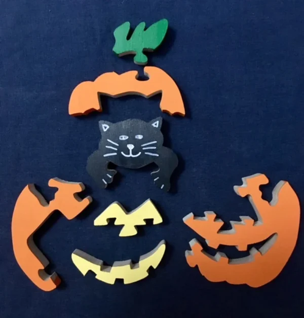 separated pieces of a painted wooden pumpkin puzzle set with a kitty playing peek-a-boo in it